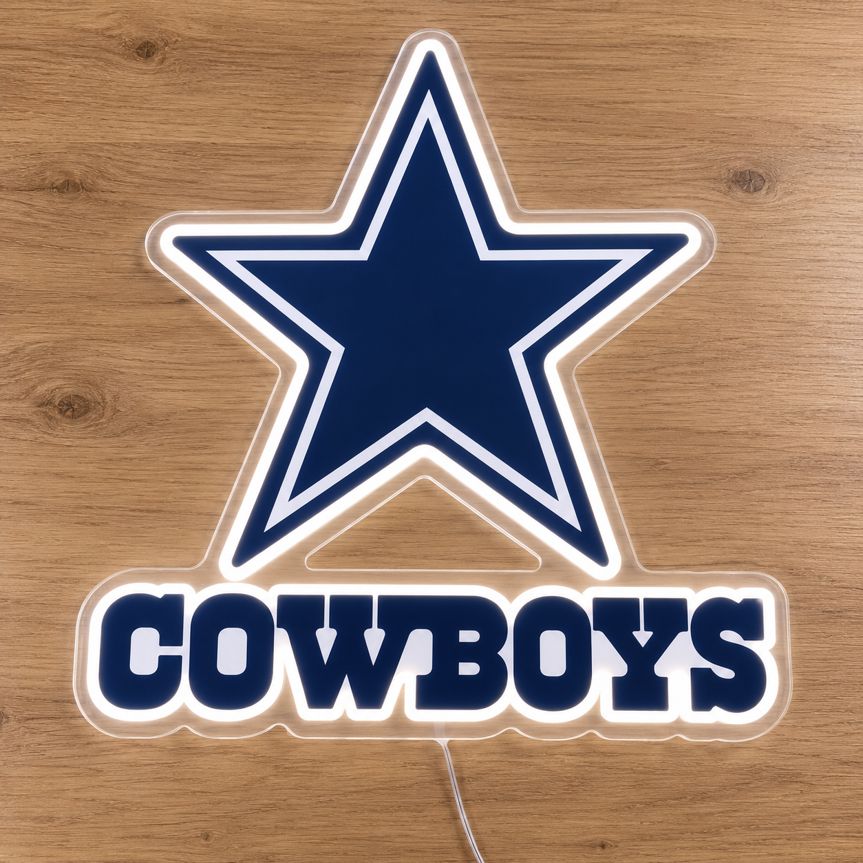 Dallas Cowboys LED light sign featuring the team's star logo and 'COWBOYS' text, shown on a light brown wooden surface.