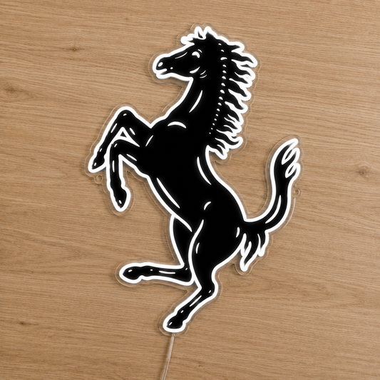 A black and white Ferrari prancing horse decal or sticker displayed on a light brown wooden surface.