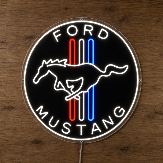 A circular Ford Mustang neon-style wall sign mounted on a wooden surface. The sign has a black background with a glowing white outline and the words “FORD” at the top and “MUSTANG” at the bottom, plus the classic horse emblem in white over vertical red, white, and blue stripes.