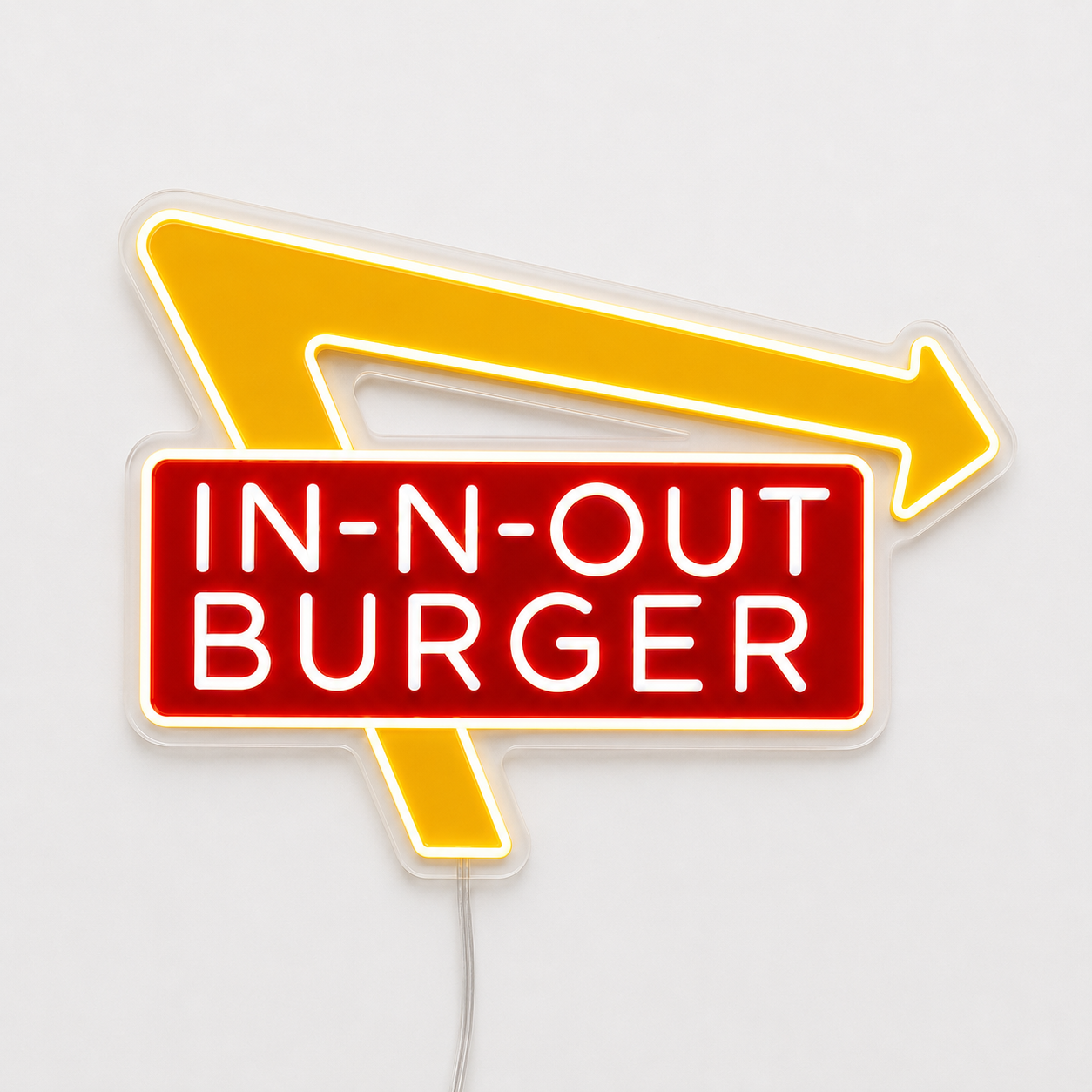 A neon-style wall sign for In-N-Out Burger, featuring a red rectangular sign with white lettering and a yellow arrow behind it, shown against a plain light background.