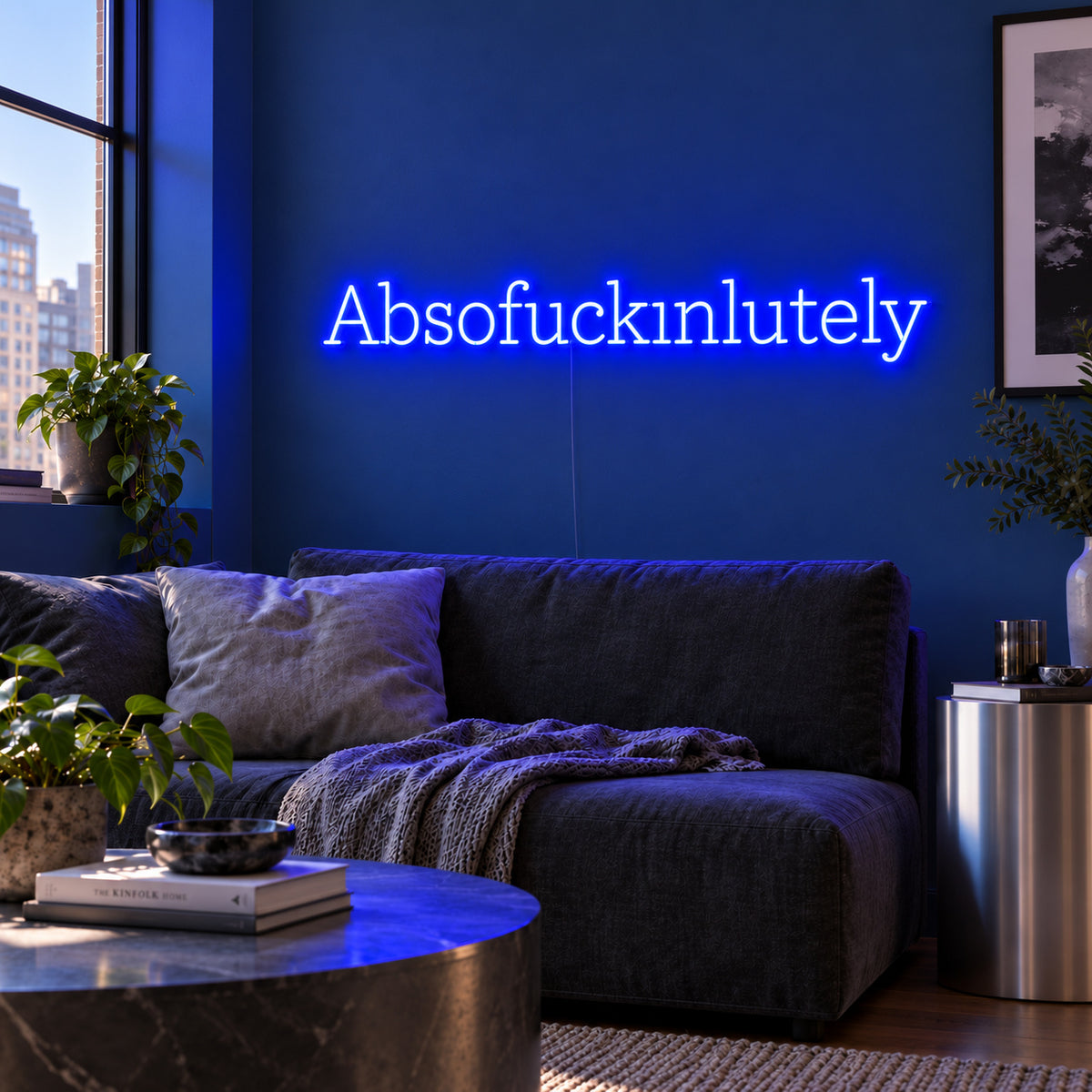 Absofuckinlutely Neon Sign glowing blue above a charcoal sofa on a blue wall.