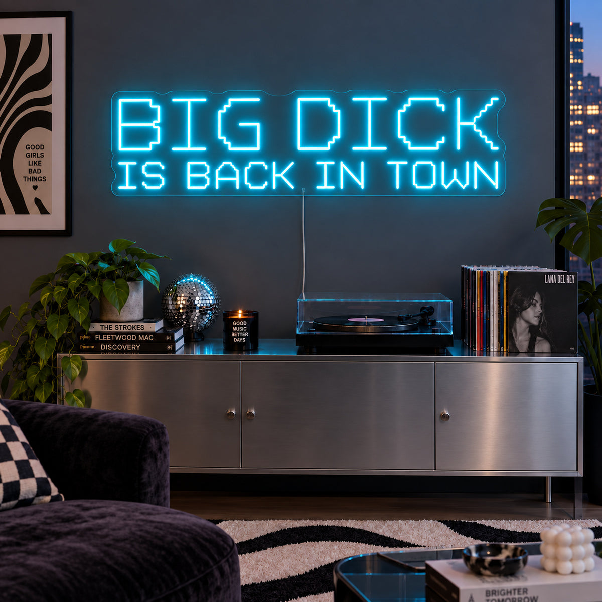 Ice Blue version of the Big Dick Is Back In Town Neon Sign, shown above a record player and metal sideboard.
