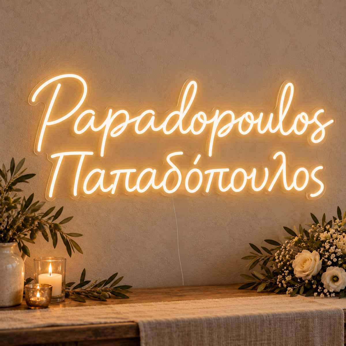 Personalised Bilingual Greek Surname Neon Sign on clear cut-to-shape acrylic in an illuminated wall display; example personalisation shown.