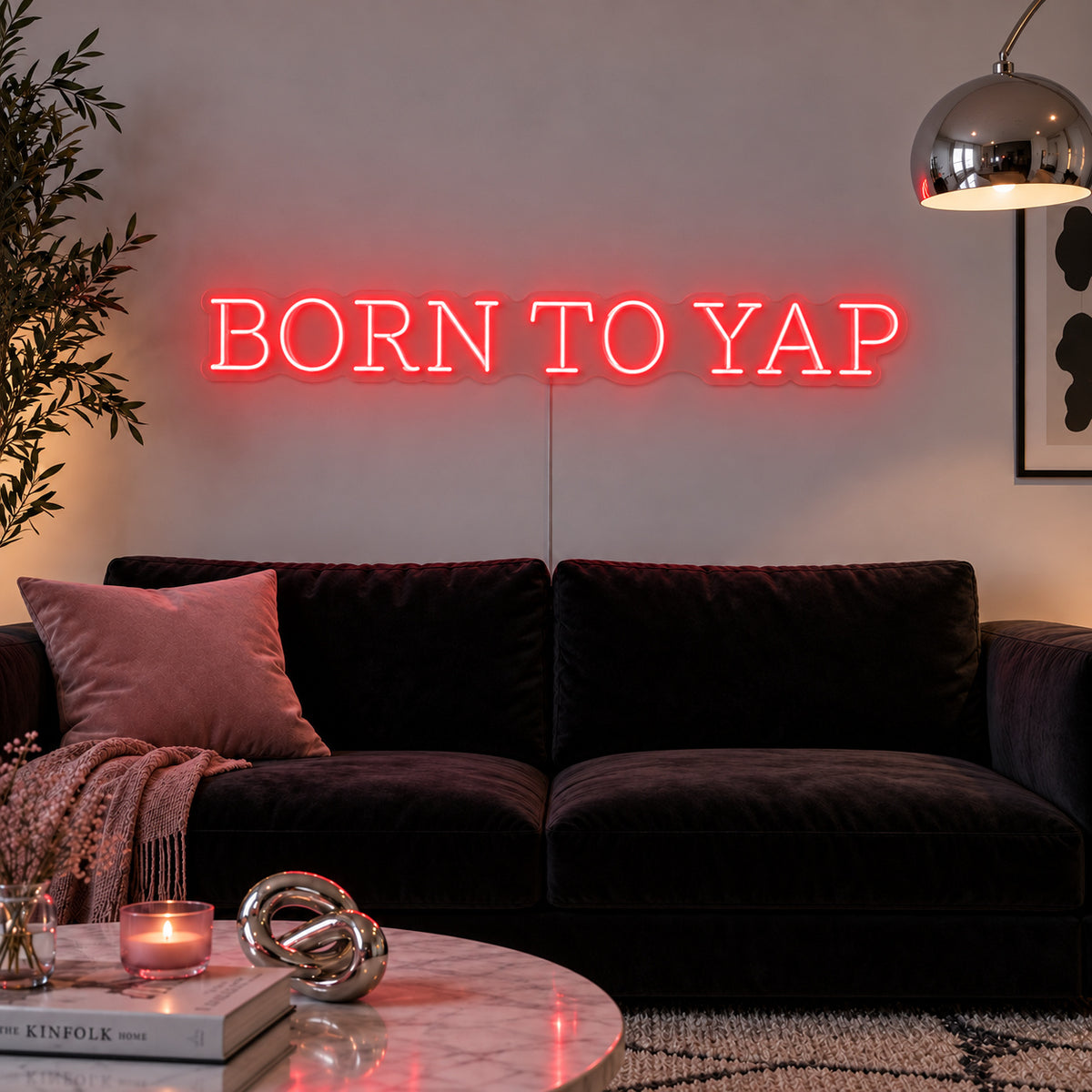 Born To Yap Neon Sign with red lighting, displayed above a dark sofa and glass coffee table.