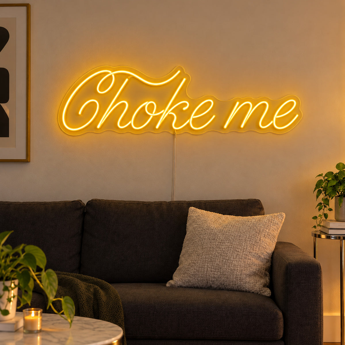 Choke Me Neon Sign glowing gold above a charcoal sofa.
