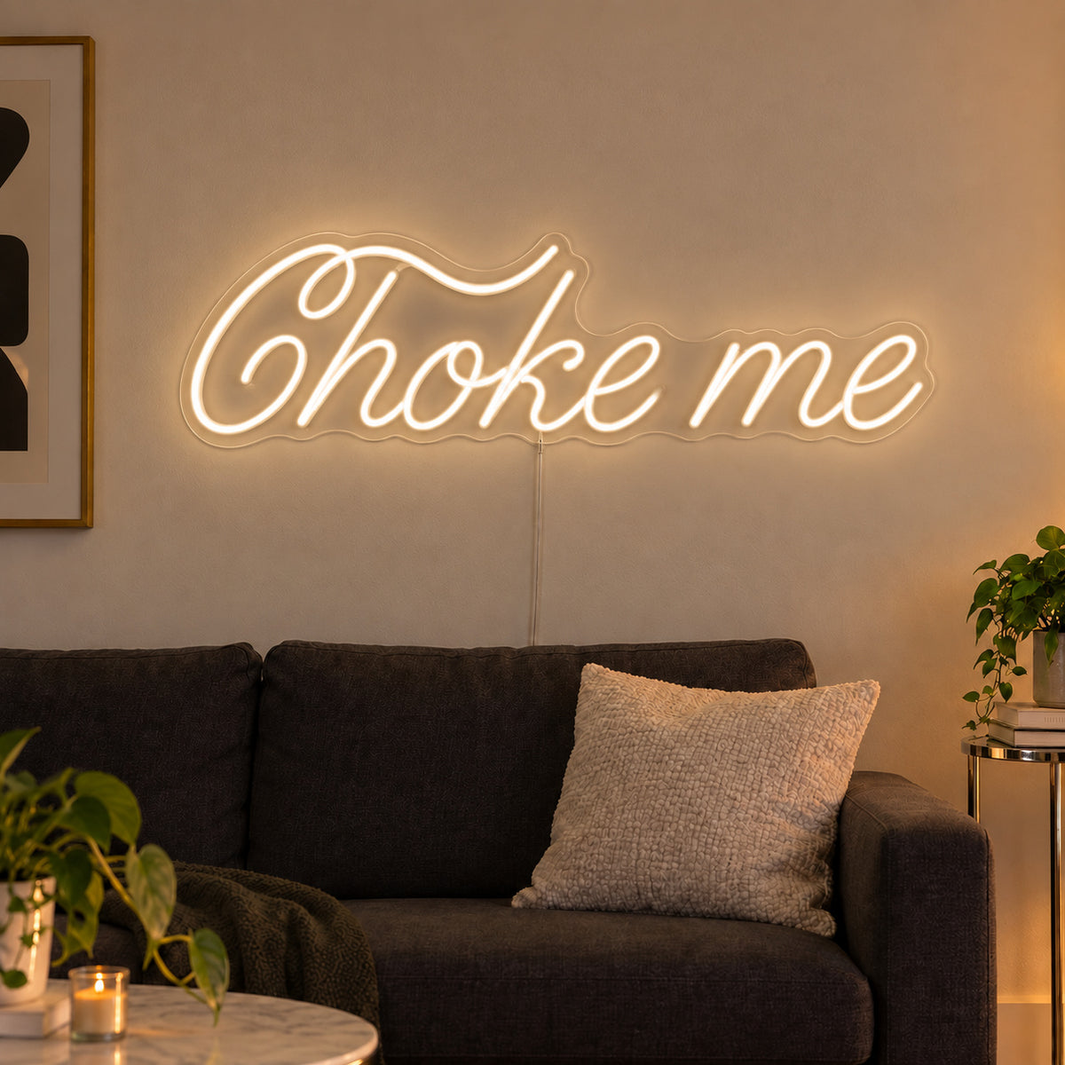 Warm White version of the Choke Me Neon Sign, shown above a charcoal sofa.