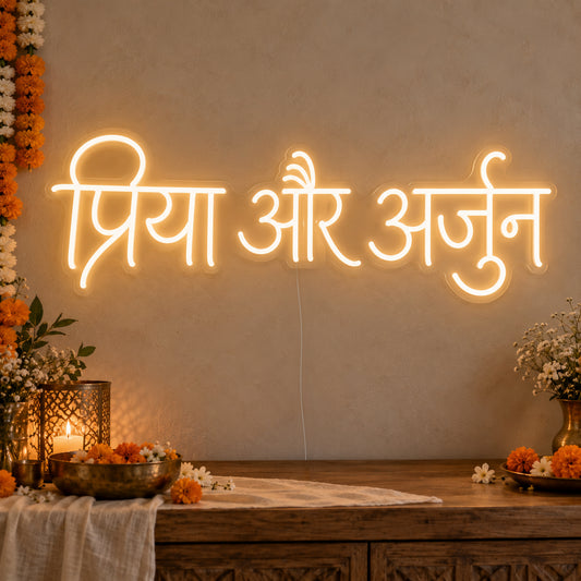 Personalised Devanagari Couple Names Neon Sign on clear cut-to-shape acrylic in an illuminated wall display; example personalisation shown.