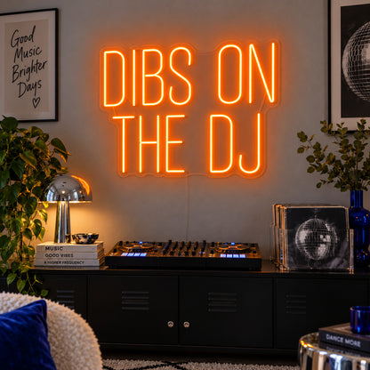 Orange version of the Dibs On The DJ Neon Sign, shown above a home DJ setup.