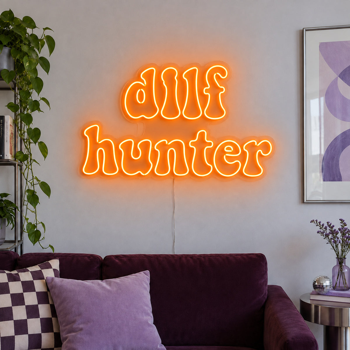 Orange version of the DILF Hunter Neon Sign, shown above a sofa with purple cushions.