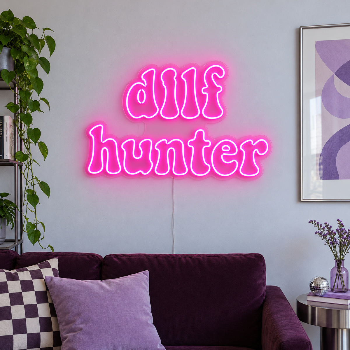 Rose Red version of the DILF Hunter Neon Sign, shown above a sofa with purple cushions.