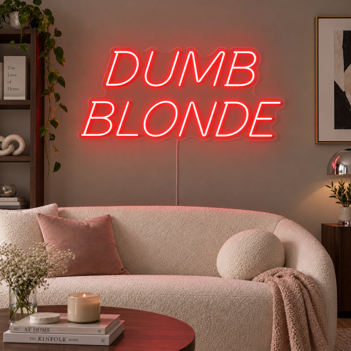 Dumb Blonde Neon Sign with red lighting, displayed in slanted lettering above a cream sofa.