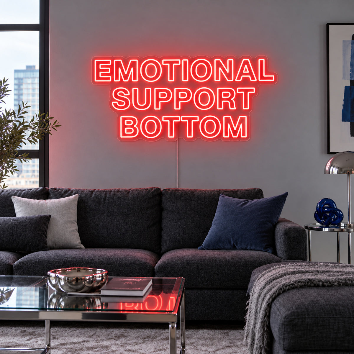 Emotional Support Bottom Neon Sign with red lighting, displayed above a charcoal sofa.