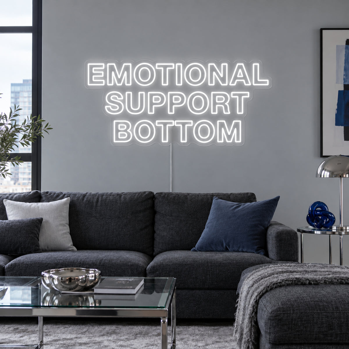 Emotional Support Bottom Neon Sign in white above a charcoal sofa.