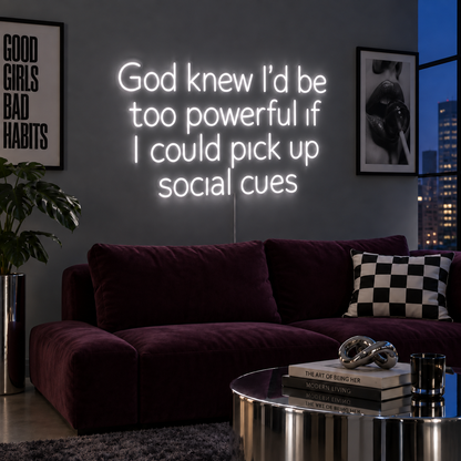God Knew I'd Be Too Powerful If I Could Pick Up Social Cues Neon Sign in white above a burgundy sofa.