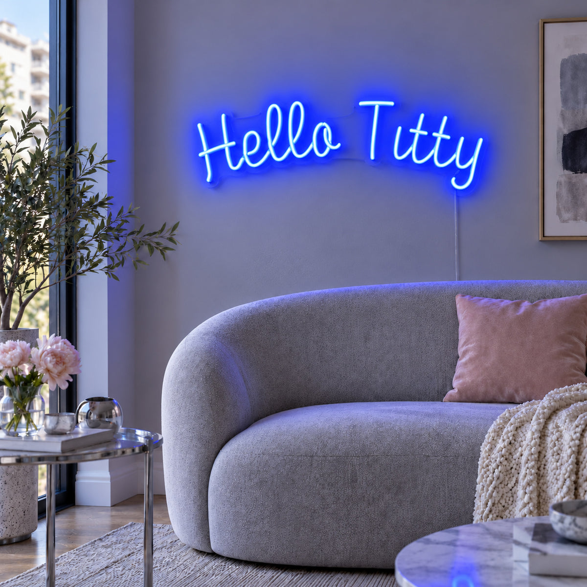 Hello Titty Neon Sign glowing blue above a curved grey sofa.