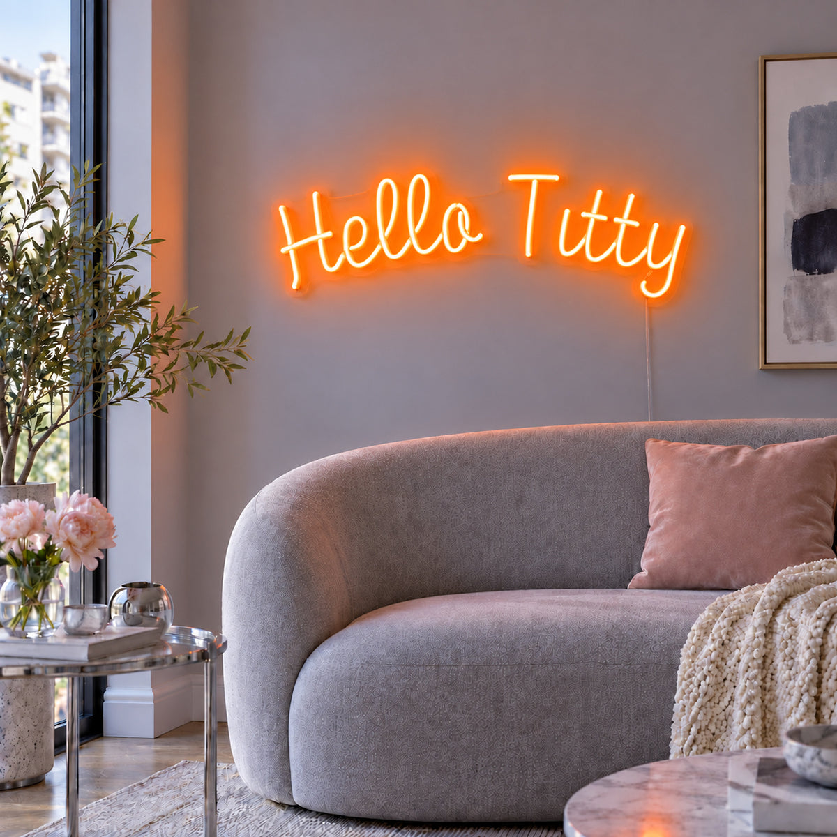 Orange version of the Hello Titty Neon Sign, shown above a curved grey sofa.