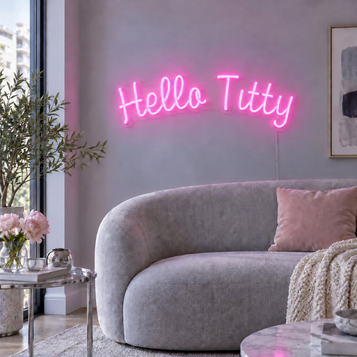 Hello Titty Neon Sign in pink above a curved grey sofa.