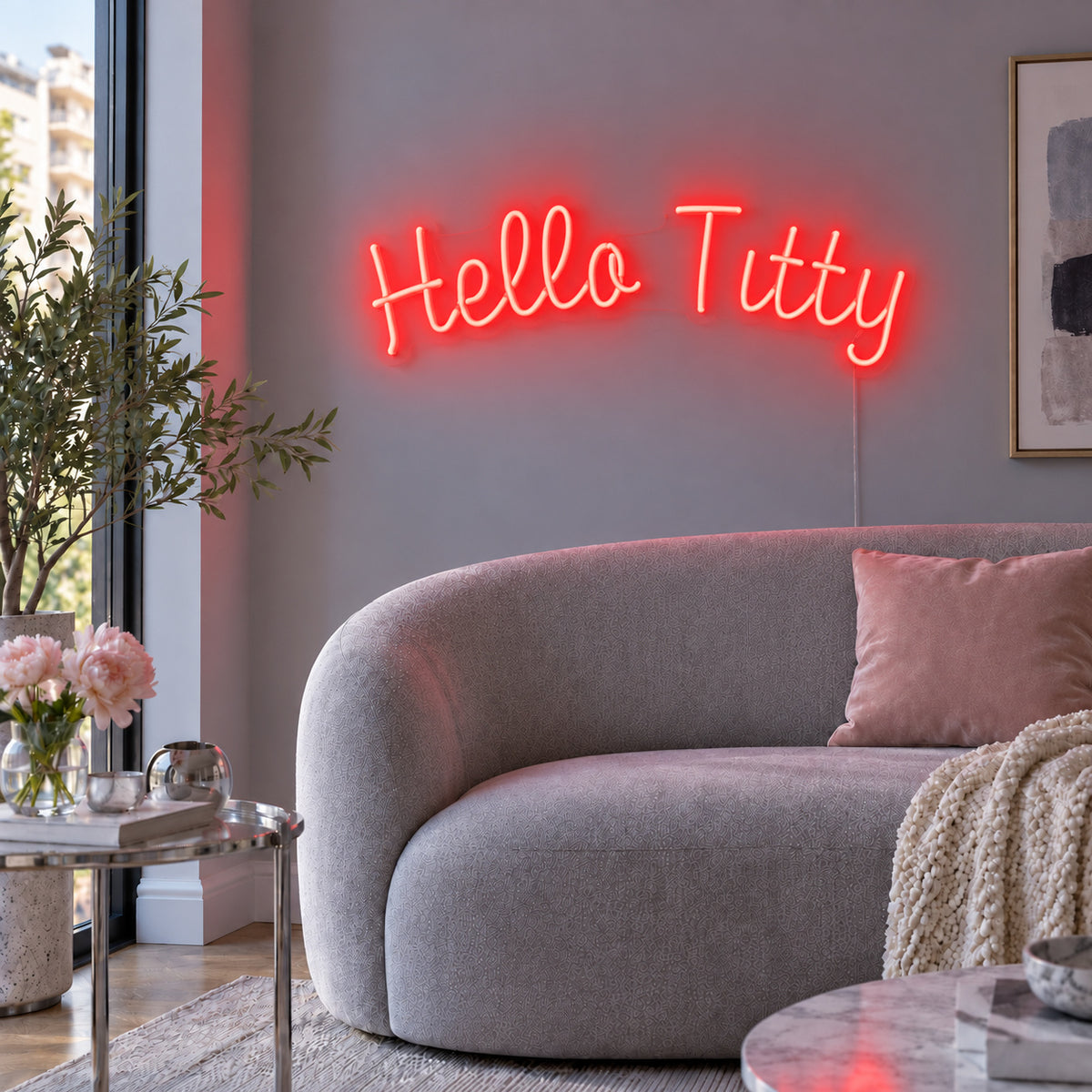 Hello Titty Neon Sign with red lighting, displayed above a curved grey sofa.