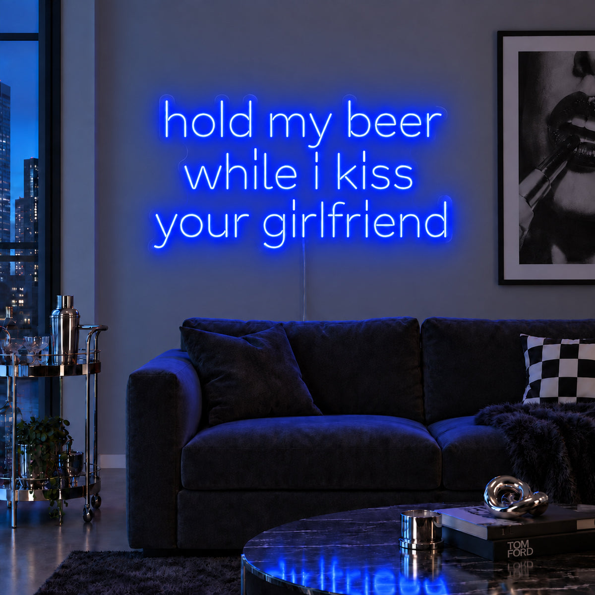 Hold My Beer While I Kiss Your Girlfriend Neon Sign glowing blue above a burgundy sofa.