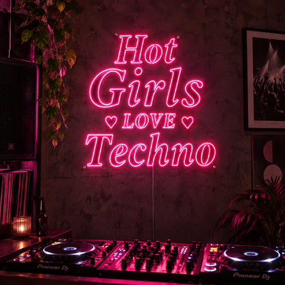 Hot Girls Love Techno Neon Sign in rose red with heart details above a DJ setup.