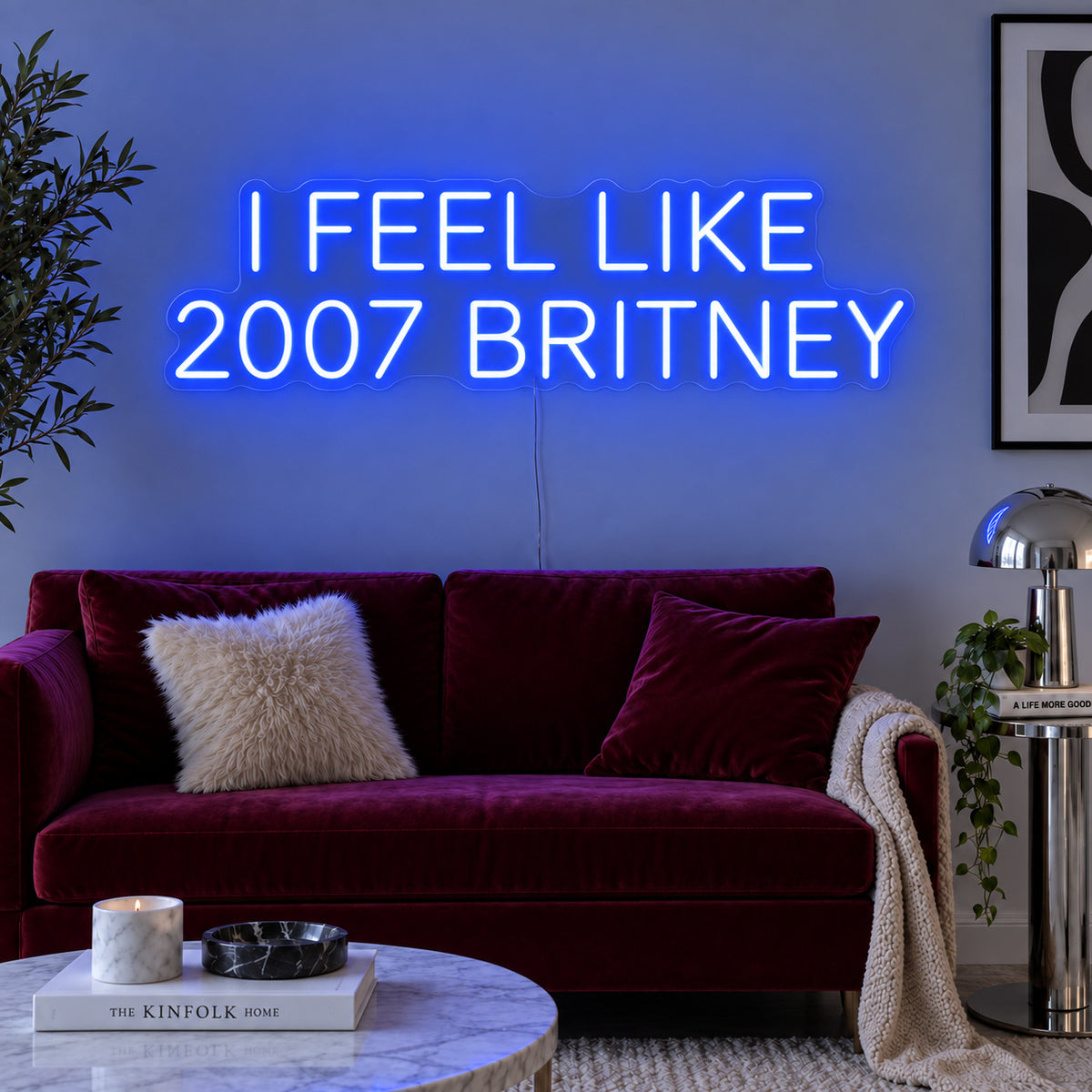 I Feel Like 2007 Britney Neon Sign glowing blue above a burgundy sofa.