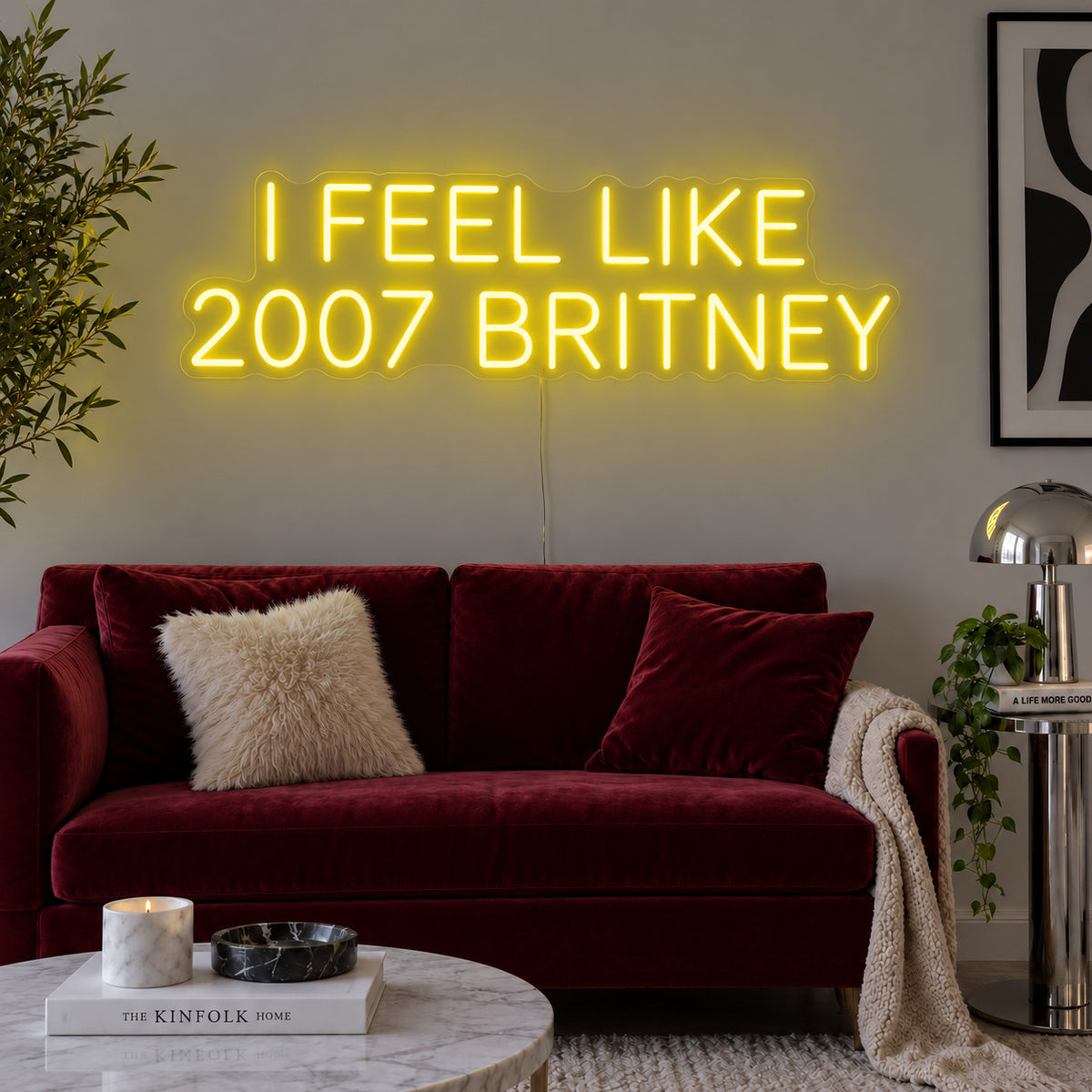 I Feel Like 2007 Britney Neon Sign with yellow lighting, displayed above a burgundy sofa.