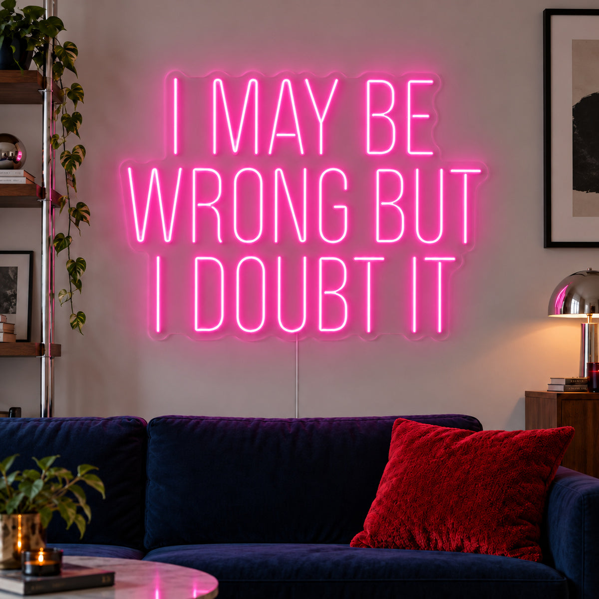 I May Be Wrong But I Doubt It Neon Sign glowing pink above a dark blue sofa.