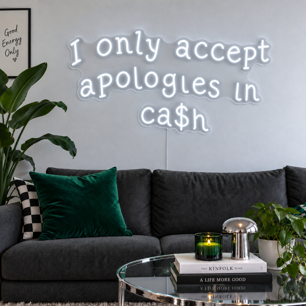 I Only Accept Apologies In Ca$h Neon Sign, RGB colour-changing option shown in white above a charcoal sofa with green cushions.
