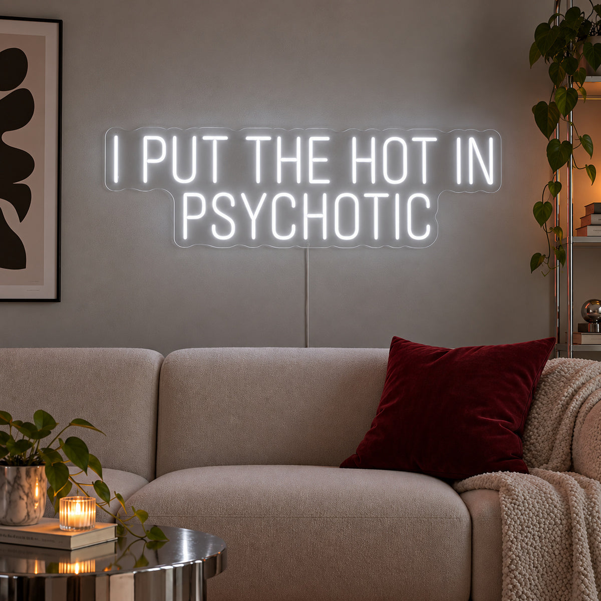 I Put The Hot In Psychotic Neon Sign glowing white above a neutral sofa.