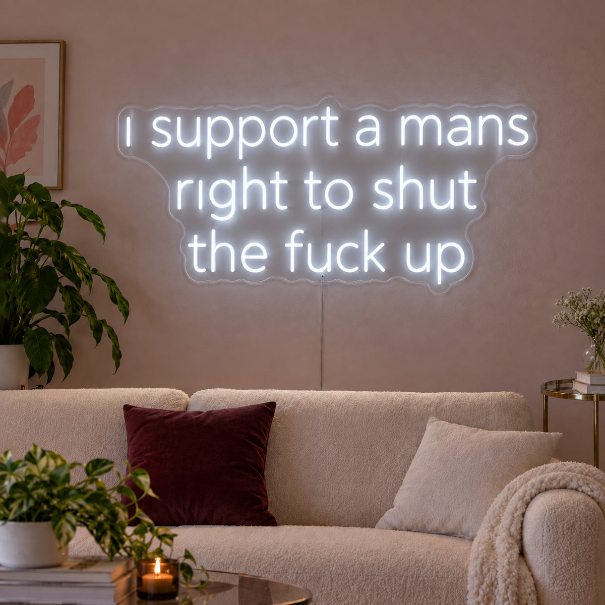 I Support A Mans Right To Shut The Fuck Up Neon Sign glowing white above a cream sofa.