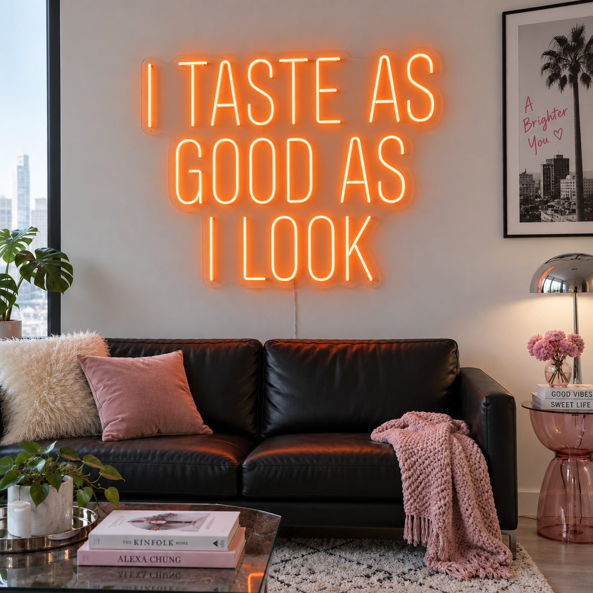 Orange version of the I Taste As Good As I Look Neon Sign, shown above a black sofa.