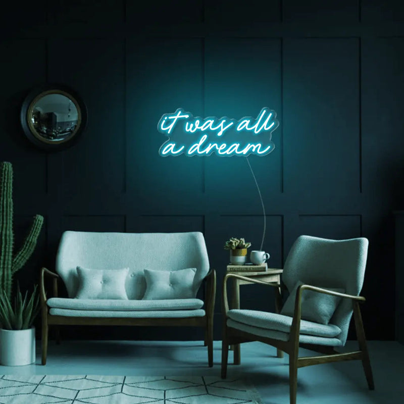 It Was All A Dream LED Neon Sign in turquoise, featuring script lettering above a small sofa on a dark panelled wall.