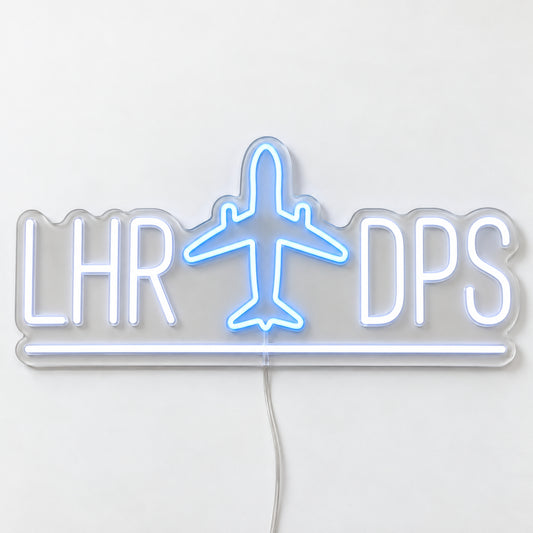 LHR to DPS Flight Route Neon Sign, featuring the LHR to DPS flight route with an aircraft motif, on a single clear acrylic backing displayed on a white surface.
