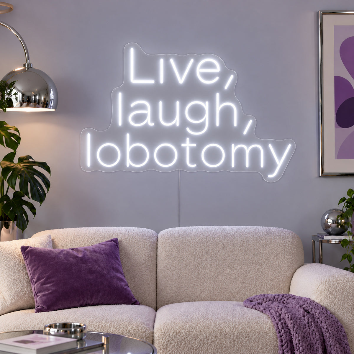 Live, Laugh, Lobotomy Neon Sign glowing white above a cream sofa with purple cushions.