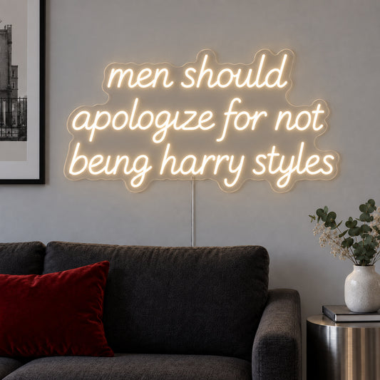 Warm White version of the Men Should Apologize For Not Being Harry Styles Neon Sign, shown above a dark sofa.