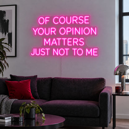 Rose Red version of the Of Course Your Opinion Matters Just Not To Me Neon Sign, shown above a black sofa.