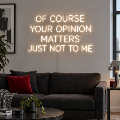 Warm White version of the Of Course Your Opinion Matters Just Not To Me Neon Sign, shown above a black sofa.